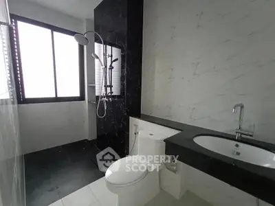 Modern bathroom with sleek black and white design, featuring a spacious shower and elegant fixtures.