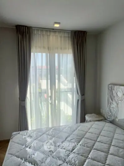 Cozy bedroom with large window and elegant curtains, offering natural light and a serene atmosphere.