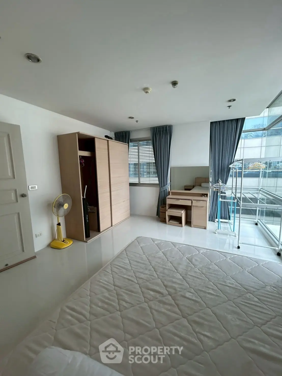 Spacious bedroom with modern furniture and large windows for natural light