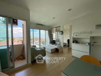 Bright living room with balcony and scenic view, modern furniture, and wooden flooring.