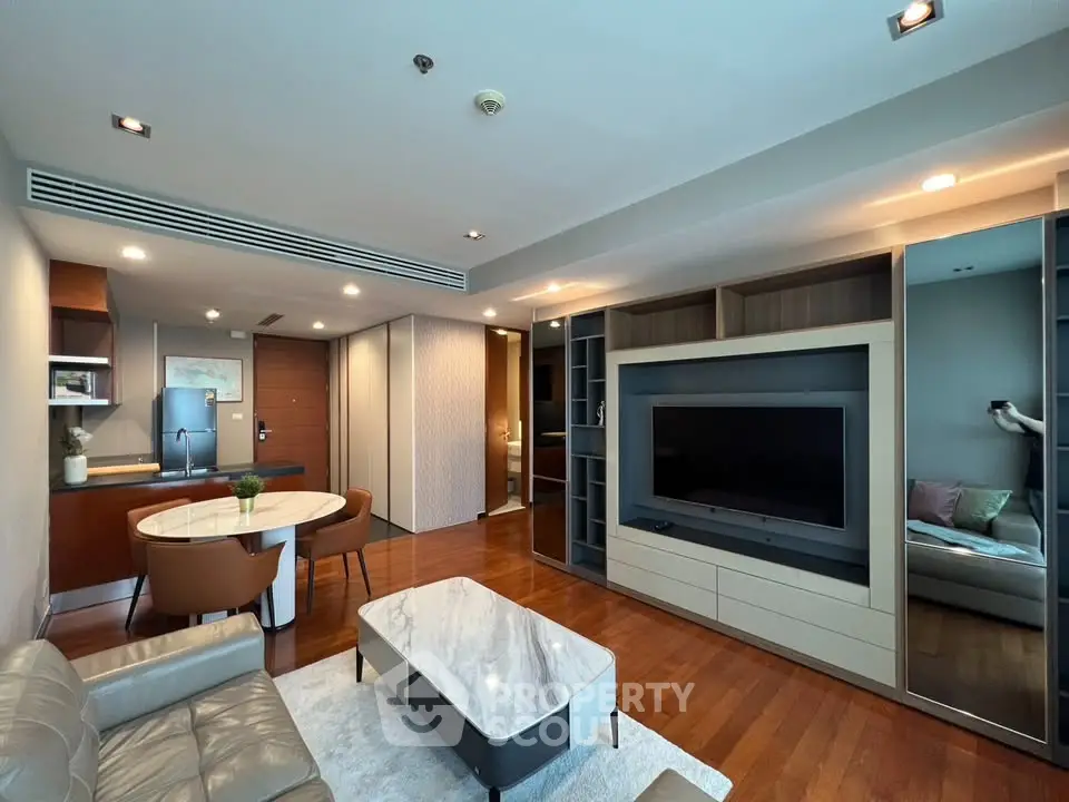 Modern living room with sleek furniture and open layout, featuring a large TV and elegant decor.