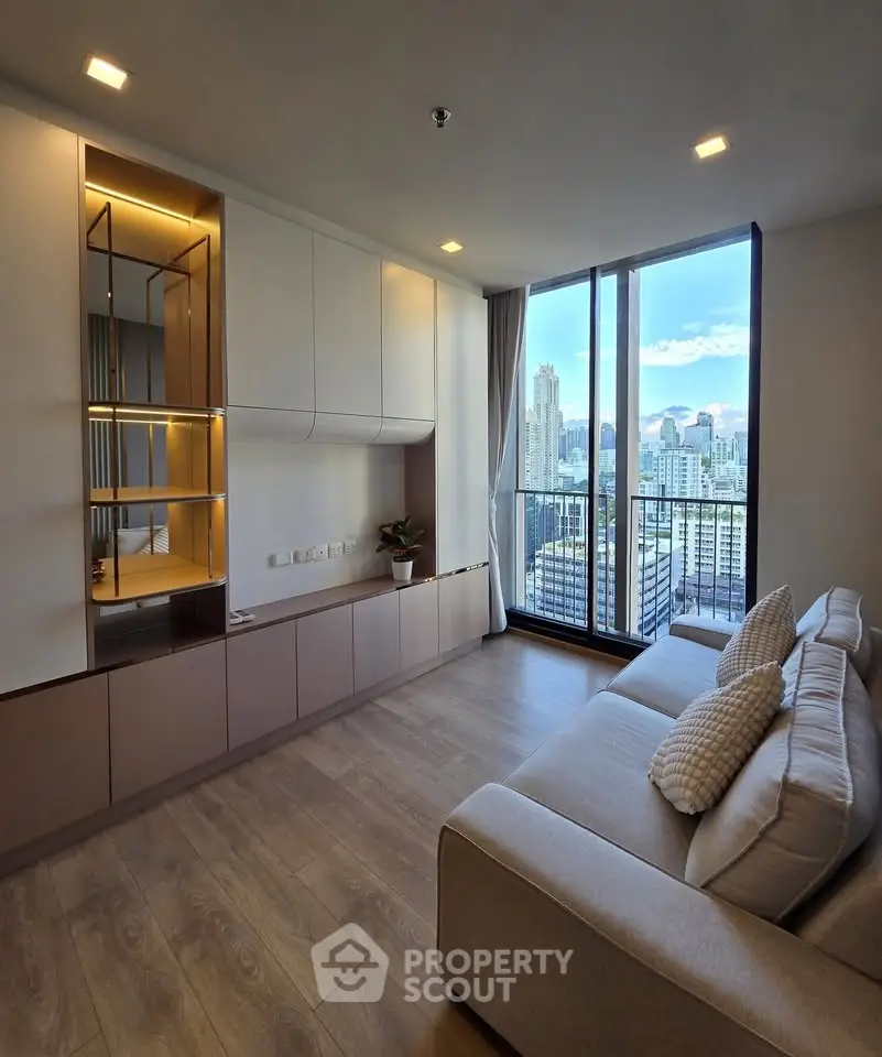 Modern living room with large windows offering stunning city views, sleek built-in storage, and cozy seating.
