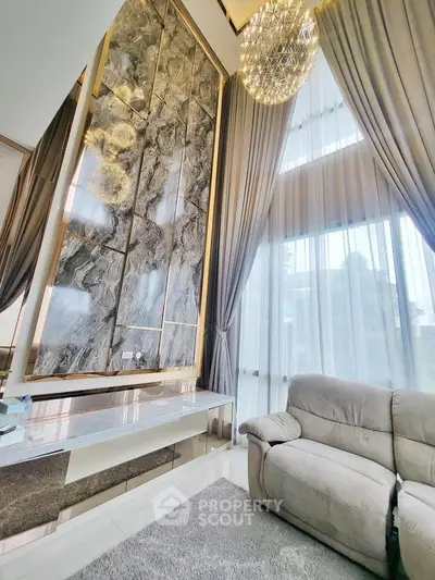 Luxurious living room with high ceilings, elegant marble wall, and plush seating in a modern home.
