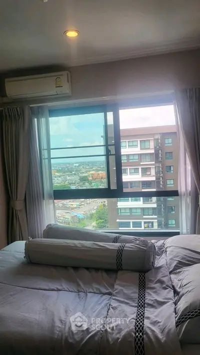 Cozy bedroom with city view, featuring a large window and elegant bedding in a modern apartment.