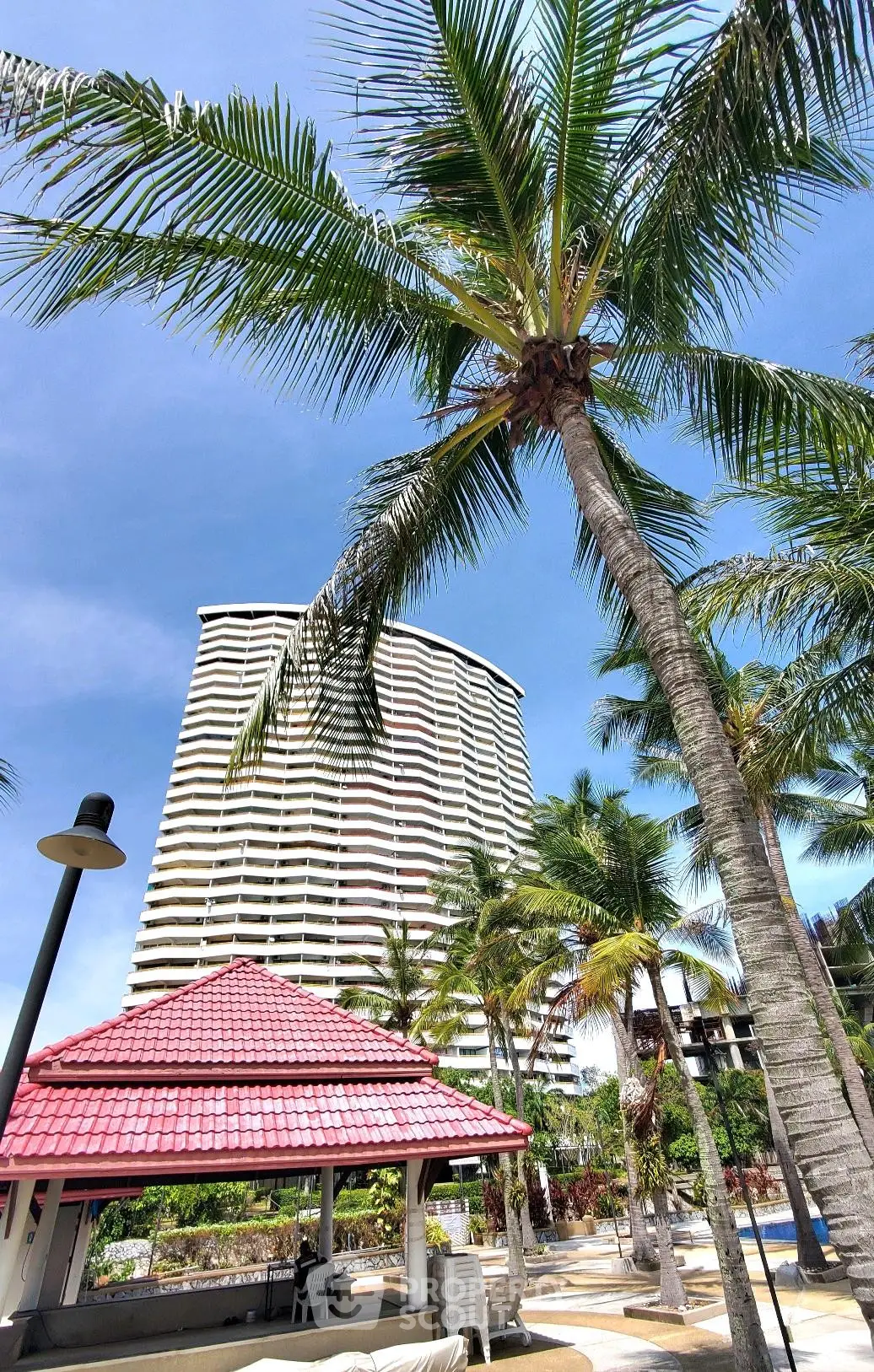 Stunning high-rise building with palm trees and outdoor amenities in a tropical setting.