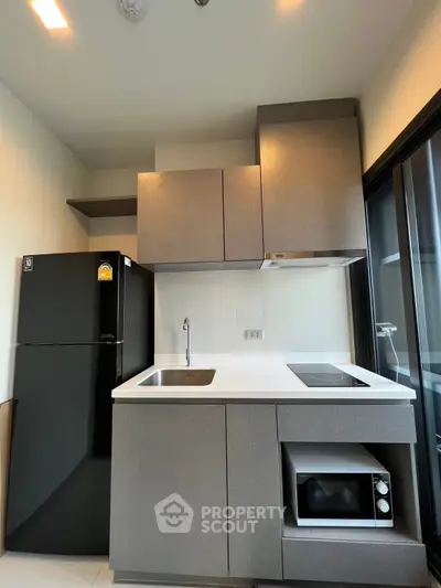Modern kitchen with sleek cabinetry, black fridge, and built-in appliances in a compact layout.