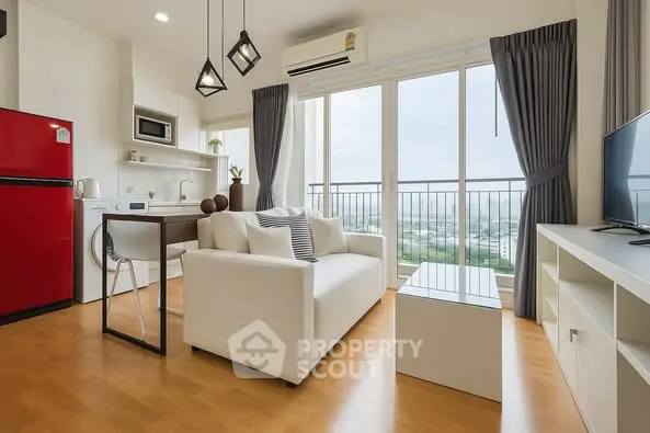 Modern living room with open kitchen and city view, featuring sleek furniture and bright natural light.