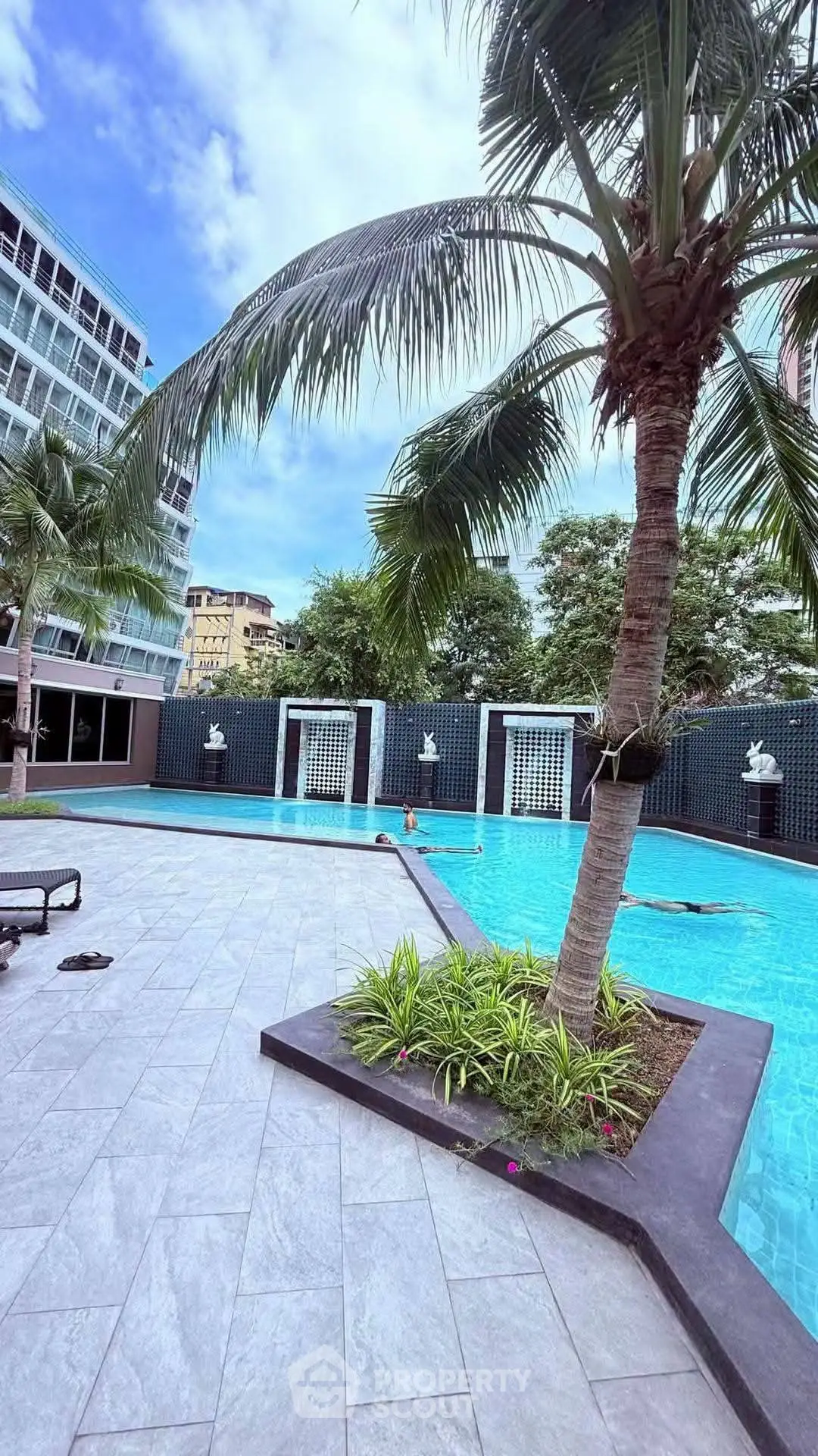 Luxurious poolside area with palm trees and modern architecture, perfect for relaxation and leisure.