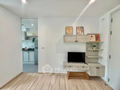 Modern living room with stylish TV unit and view into sleek kitchen