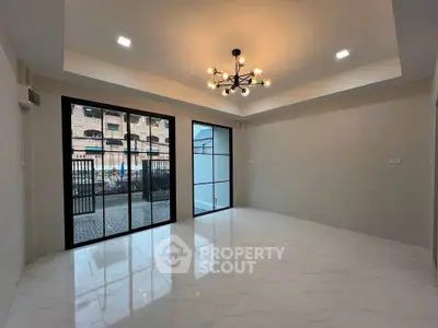 Spacious modern living room with elegant chandelier and large windows offering ample natural light.