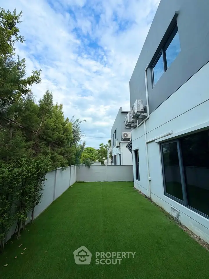 Modern townhouse with lush green backyard and sleek exterior design.