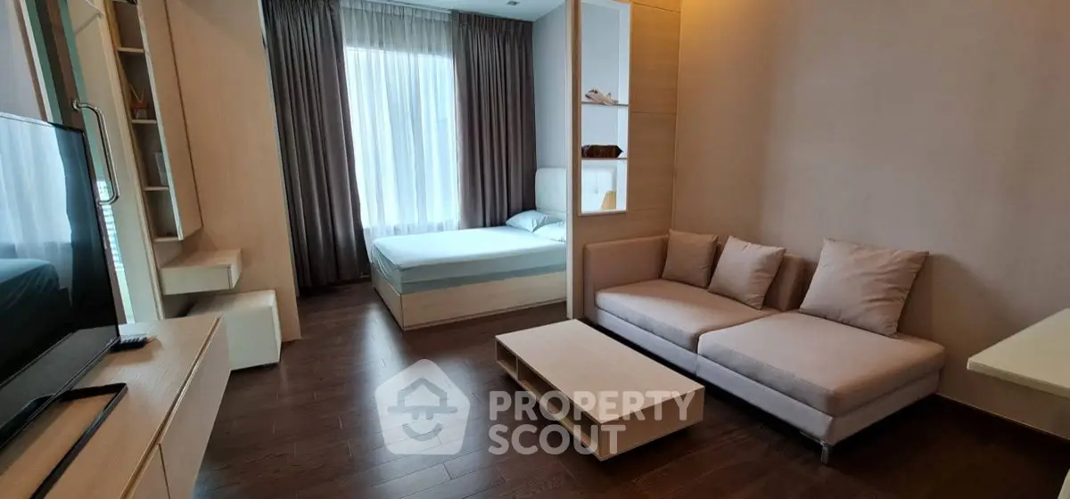 Modern studio apartment with cozy living area and bedroom, featuring elegant wooden flooring and stylish decor.
