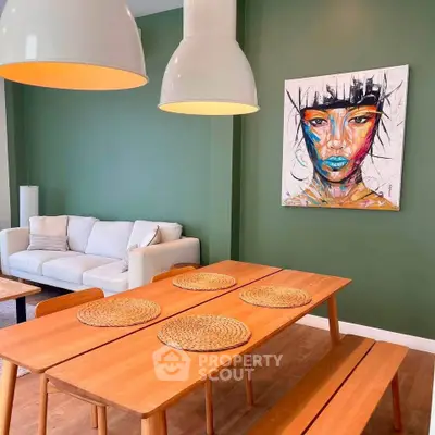 Stylish dining area with wooden table, green walls, and modern art in a cozy living room.