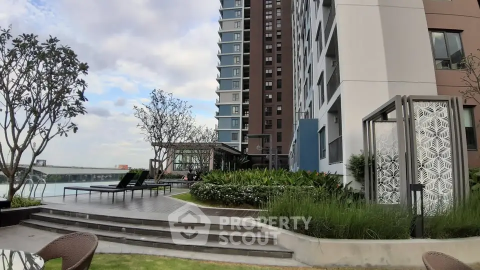 Modern apartment building with lush garden and poolside lounge area
