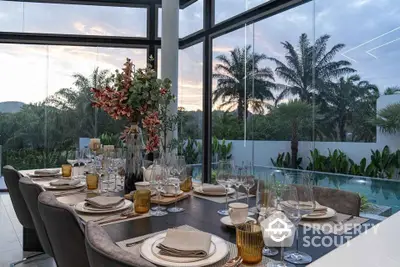 Luxurious dining area with panoramic glass walls overlooking tropical garden and pool