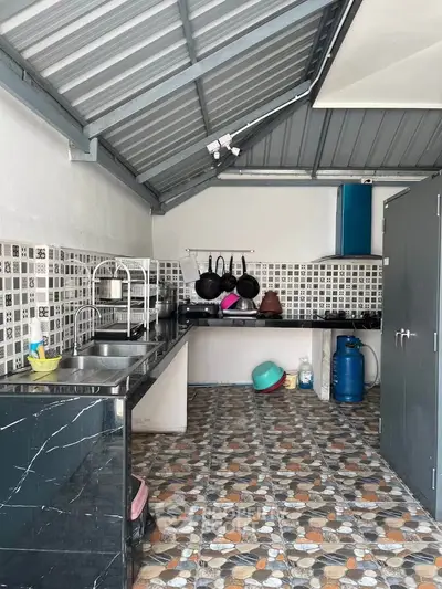 Spacious kitchen with modern tiled flooring and ample counter space, featuring a gas stove and sleek metal roof.