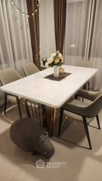 Elegant dining area with modern table, plush chairs, and decorative centerpiece.