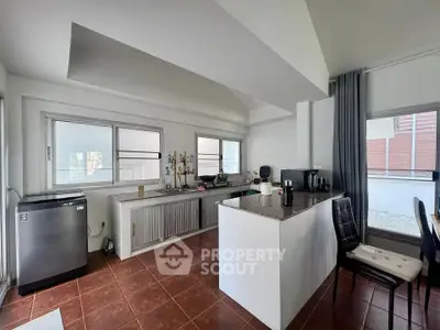Spacious kitchen with modern appliances and open layout, featuring large windows and stylish decor.