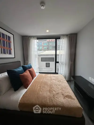 Modern bedroom with stylish decor and large window offering natural light.