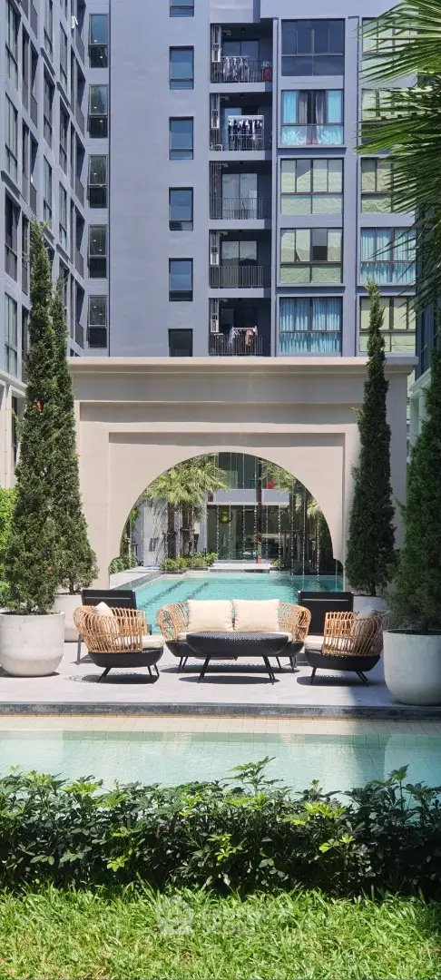 Luxurious apartment complex with elegant poolside seating and lush greenery