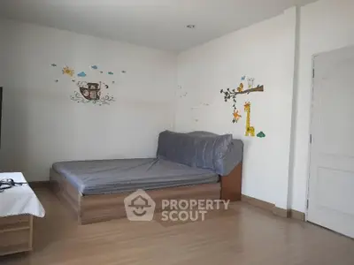 Spacious bedroom with wooden flooring and playful wall decals, perfect for a cozy and inviting atmosphere.