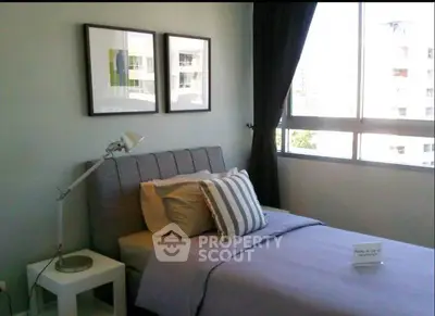 Cozy bedroom with modern decor and large window offering natural light.