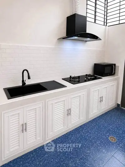 Modern kitchen with sleek black appliances and white cabinetry, featuring a gas stove and microwave.
