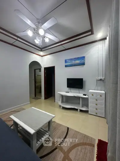 Cozy living room with modern ceiling fan and TV setup, ideal for relaxation.