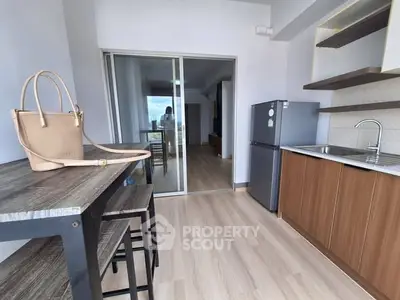 Modern kitchen with sleek design, featuring a compact fridge, stylish wooden cabinets, and a chic dining area.