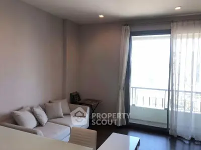 Cozy living room with modern sofa and large window offering natural light and balcony access.