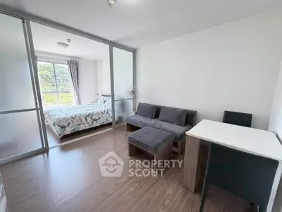 Modern apartment with sliding glass doors, cozy living area, and bright bedroom with large window.
