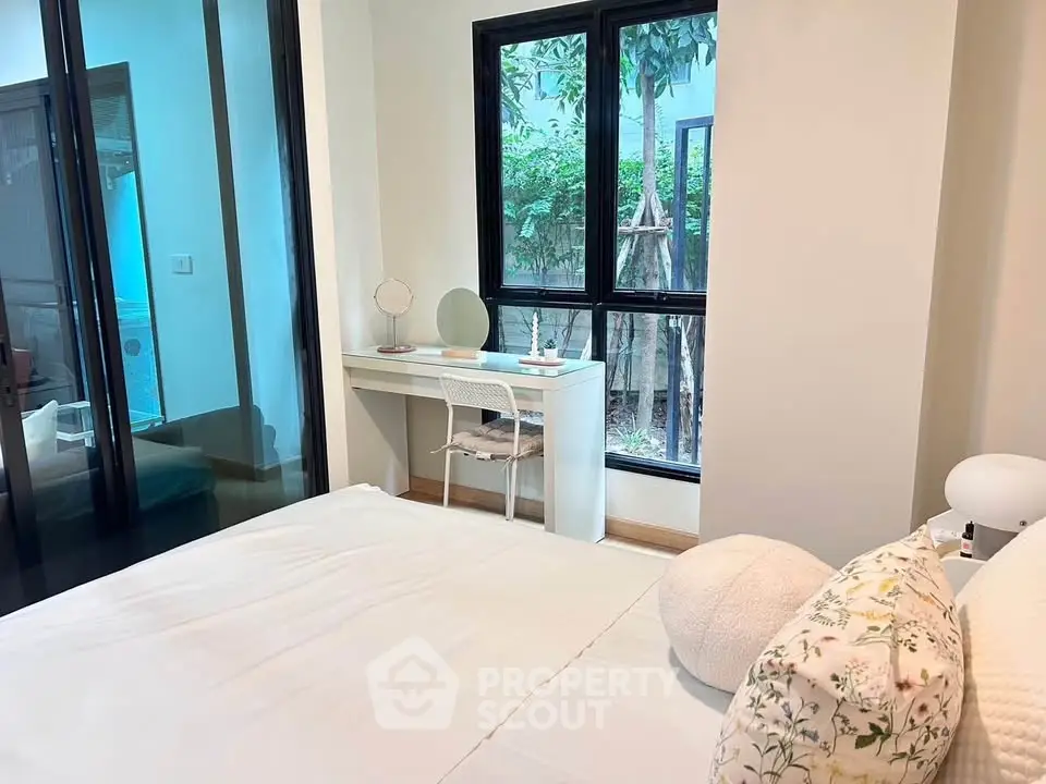 Cozy bedroom with large window and stylish decor, perfect for relaxation and comfort.