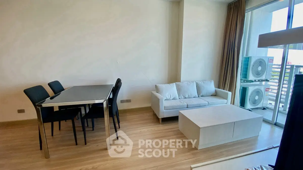 Modern living room with sleek furniture and balcony view, perfect for urban living.