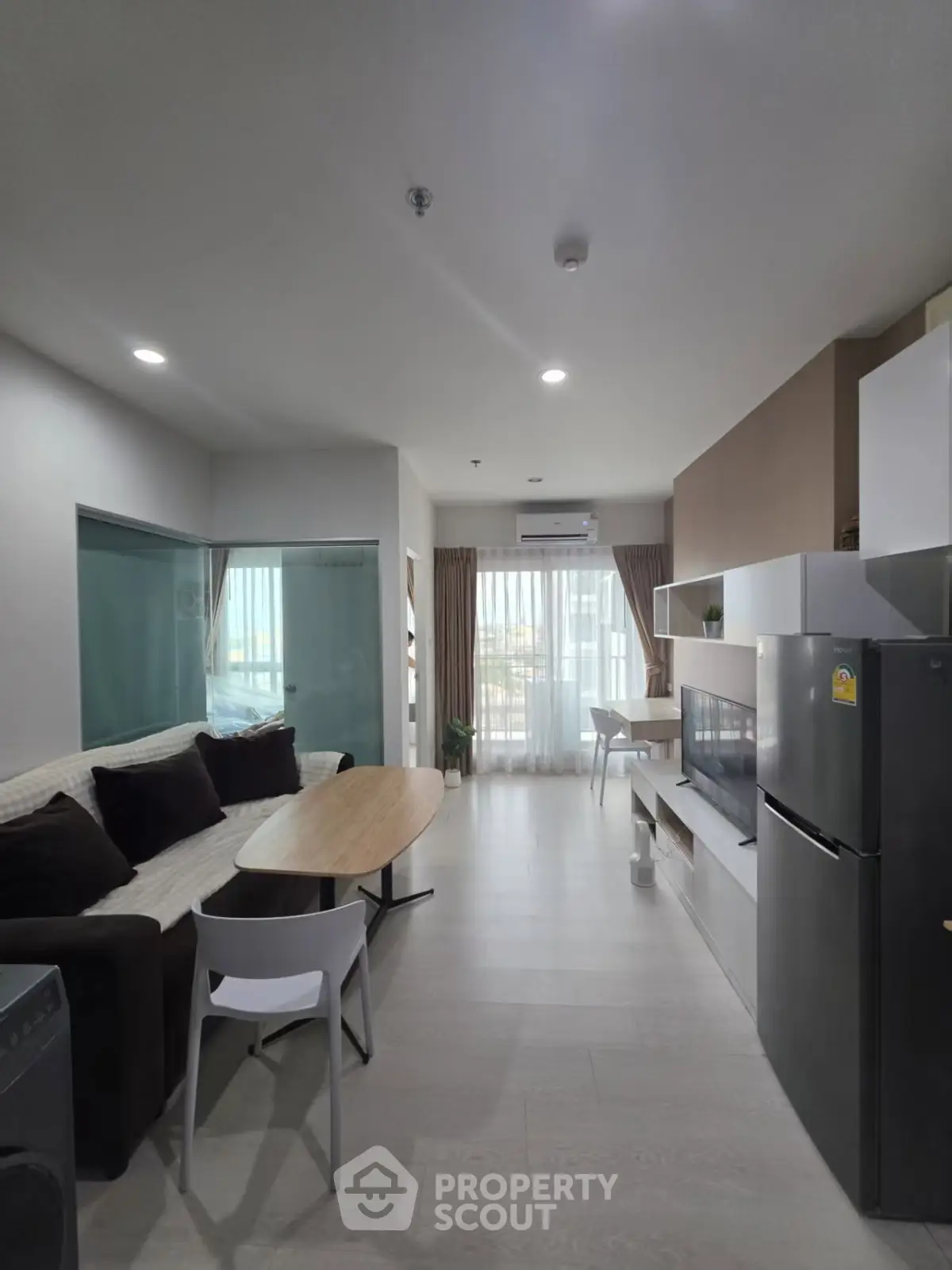 Modern living room with open layout, featuring cozy seating and sleek kitchen appliances.