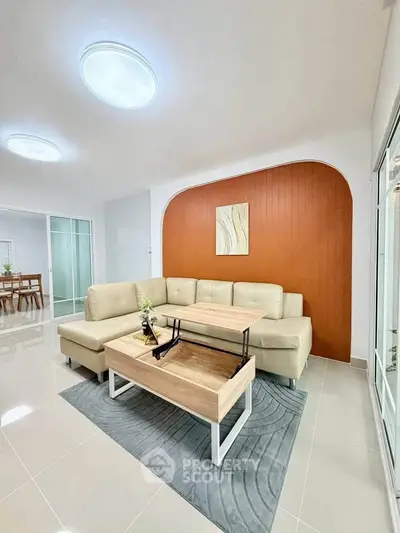 Modern living room with stylish beige sofa and wooden coffee table, featuring elegant decor and bright lighting.
