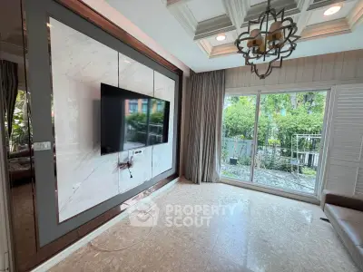 Luxurious living room with modern TV setup and garden view through large windows.