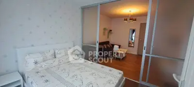 Modern bedroom with sliding glass doors leading to a cozy living area, featuring stylish decor and warm lighting.