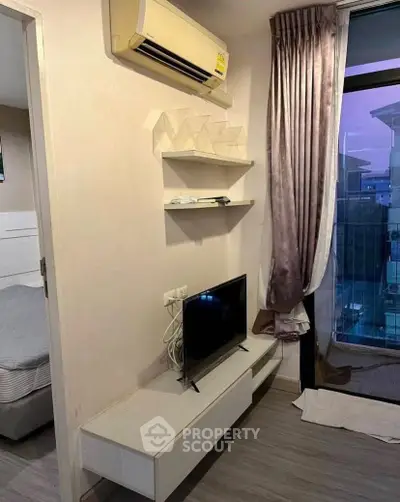 Modern living room with air conditioning, TV, and balcony access in a stylish apartment.