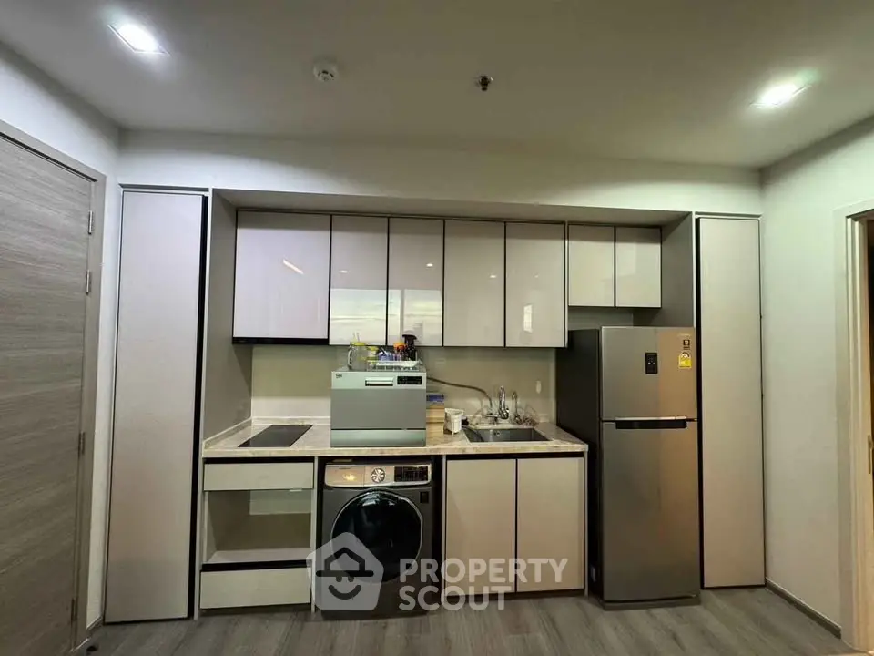 Modern kitchen with sleek cabinetry and built-in appliances, featuring a washing machine and fridge.