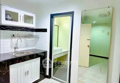 Modern kitchen with sleek black and white cabinetry and adjacent bathroom view.