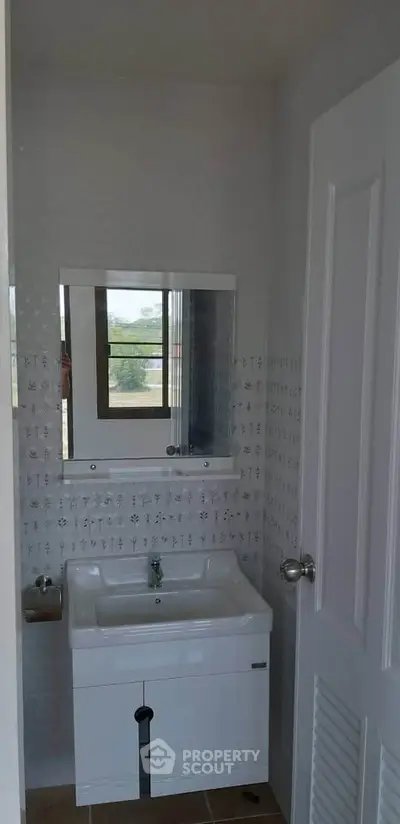 Compact bathroom with modern sink and mirror, featuring natural light from window.
