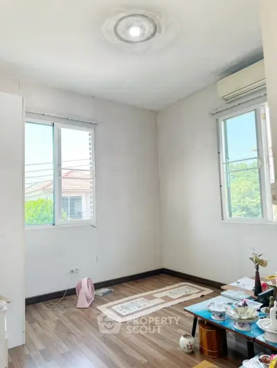 Bright room with wooden flooring and large windows, ideal for cozy living space.