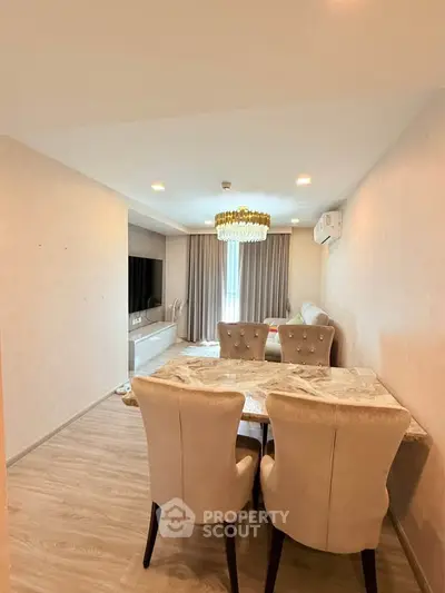 Elegant living room with modern decor and dining area, featuring a stylish chandelier and cozy seating.