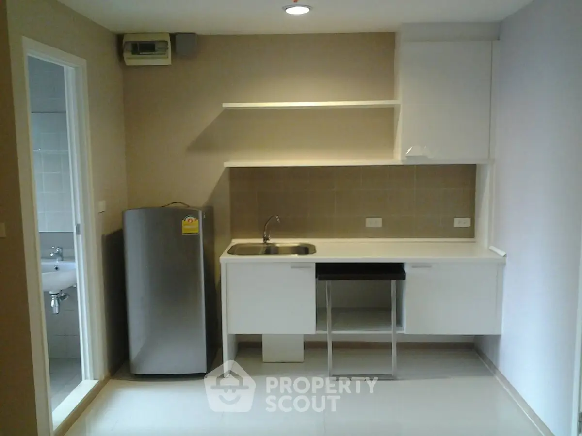 Modern kitchen with sleek cabinetry and stainless steel fridge in a compact apartment layout.