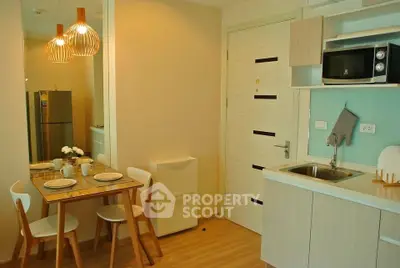 Cozy modern kitchen with dining area and stylish lighting in compact apartment.