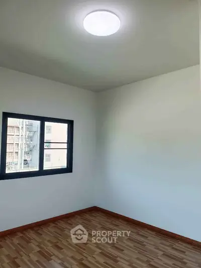Bright empty room with wooden flooring and a window, ideal for customization.