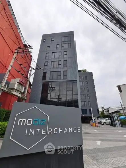 Modern urban apartment building with sleek design and prominent signage, ideal for city living.