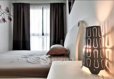 Cozy bedroom with modern lamp and natural light through window curtains.