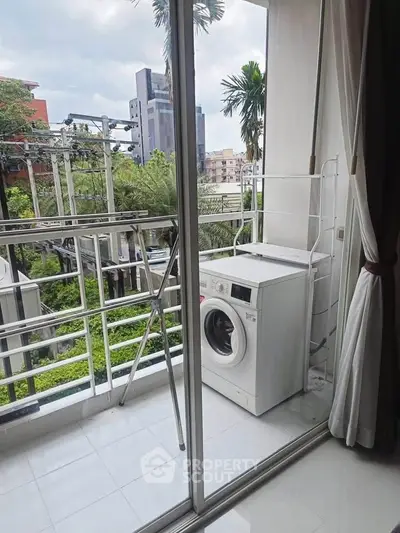 Modern balcony with washing machine and lush green view in urban setting