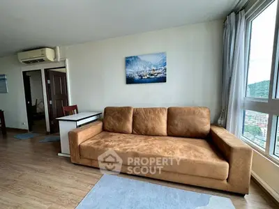 Spacious living room with large sofa and scenic window view in modern apartment.